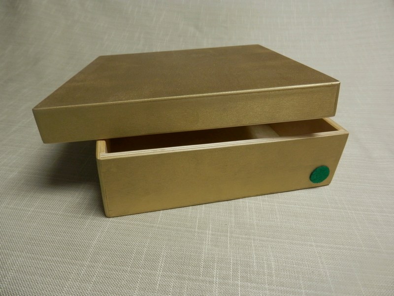 Gold box with green dot, lid slightly ajar.